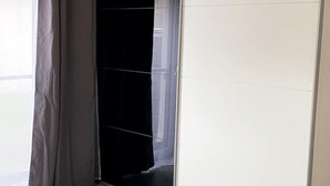 A room with a large window, a black curtain, and a white tiled wall.