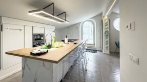 A modern kitchen with a marble island, stainless steel appliances, and a long counter. - Luxury Vatican Penthouse with 2 terraces & hot-tub (Roma)