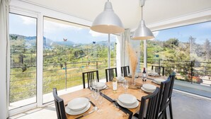 Ein Essbereich mit einem Tisch für sechs Personen, große Fenster mit landschaftlichem Ausblick auf die ländliche Umgebung.