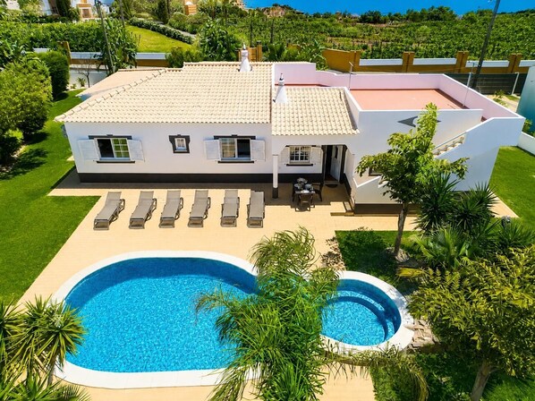 A modern house with a swimming pool, sun loungers, and a well-maintained garden. - Casa Amendoeira Large Private Pool, WiFi (Albufeira)