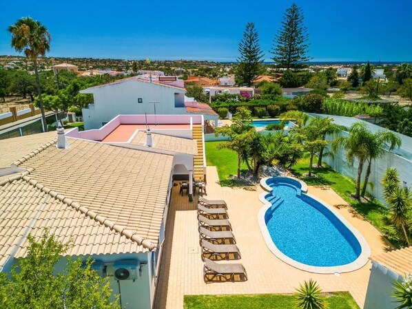 A rooftop with a swimming pool, lounge chairs, and a view of the surrounding neighborhood. - Casa Amendoeira Large Private Pool, WiFi (Albufeira)