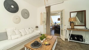 Un salon moderne avec un canapé blanc, une table basse en bois et des œuvres d’art décoratives accrochées au mur.