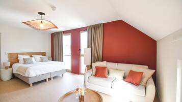 Quarto de hotel moderno com cama, sofá, mesa de centro e ventoinha no teto.