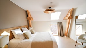Ein Schlafzimmer mit einem großen Bett, einem Holzkopfende, einem Deckenventilator und einem Fenster mit Vorhängen.