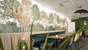 Ein Restaurant mit einer grünen gepolsterten Bank, Holztischen und gelben Stühlen.