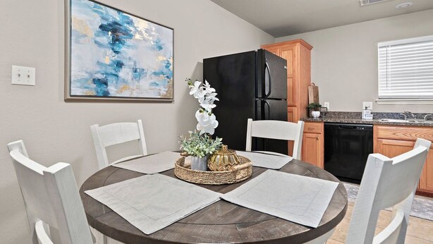 A dining area with a round table, white chairs, and a centerpiece. -   “Spacious 4-Bed Home: Dual Entrances, Work-Friendly” (Fort Smith)