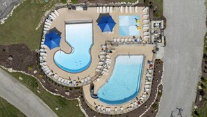 Vue aérienne d’un complexe hôtelier doté de deux grandes piscines, de chaises longues et de parasols.