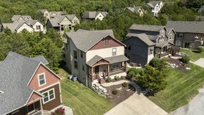 Un quartier résidentiel composé de plusieurs maisons, chacune présentant un style architectural distinct, et entouré d’une végétation luxuriante.