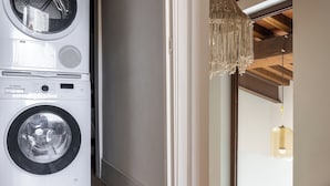 A stacked washer and dryer unit in a hallway with a wooden ceiling and a hanging light fixture. - Melaiolo Modern Apartment With Pool Montaione (Montaione)
