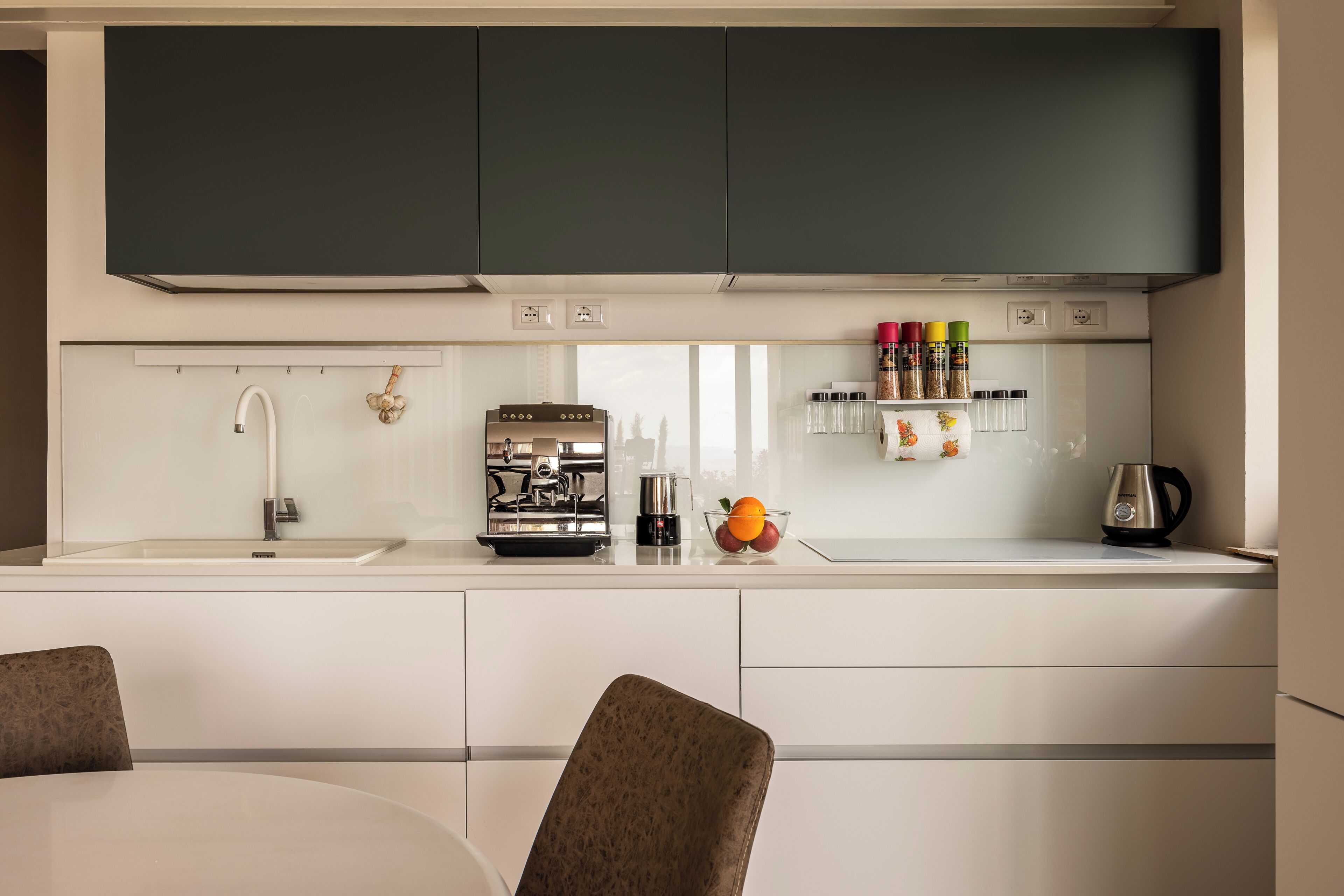 A modern kitchen with a built-in stove, a coffee maker, and a fruit bowl.