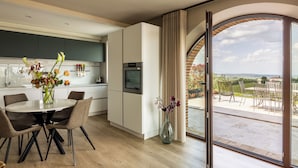 A modern kitchen with a dining area, large windows, and a view of the outdoors. - Melaiolo Modern Apartment With Pool Montaione (Montaione)