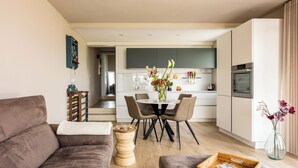 A modern living room with a sofa, a coffee table, and a dining area with chairs and a table. - Melaiolo Modern Apartment With Pool Montaione (Montaione)