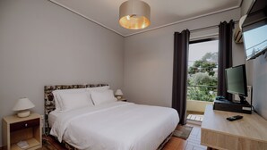 A bedroom with a bed, bedside tables, a desk with a computer, and a window with curtains.