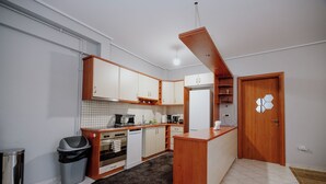 A compact kitchen with white cabinets, a built-in oven, a dishwasher, and a small island with a sink.