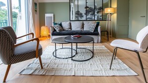 Ein modernes Wohnzimmer mit einer Couch, zwei runden Tischen und einem gemusterten Teppich.