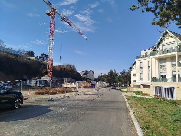 A residential street with a construction crane, parked cars, and houses.