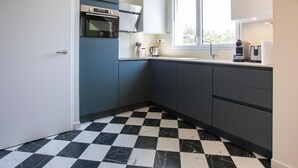 Eine Küche mit Schachbrettfliesen in Schwarz und Weiß, einem Einbauofen und einem Fenster, das für natürliches Licht sorgt.
