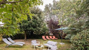 Un jardin avec un espace aménagé comprenant des fauteuils de détente, une petite table et une table à manger.