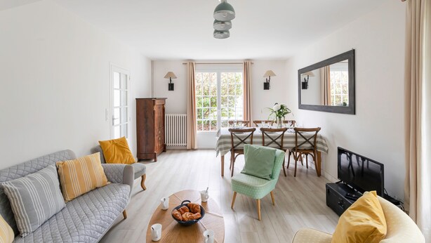 Un salon spacieux comprenant un canapé, un fauteuil, une table à manger et un téléviseur.