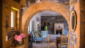 Un arco de piedra que conduce a una sala de estar con chimenea, televisor y comedor.