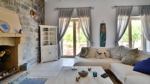 Una sala de estar con pared de piedra, chimenea, sofá y mesa de centro.