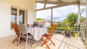 A covered patio with a table set for two, surrounded by wooden chairs, and a potted plant. - Ecrin Marin - apt terrasse, bassin d'arcachon (La Teste-de-Buch)