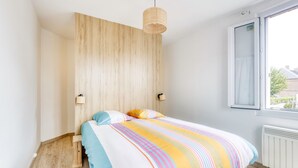 A bedroom with a bed, a window, and a wooden wall. - Les Brises Normandes - Entre mer, falaises et GR21 (Saint-Pierre-en-Port)