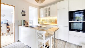 A modern kitchen with white cabinets, a wooden island, and a black oven. - Les Brises Normandes - Entre mer, falaises et GR21 (Saint-Pierre-en-Port)