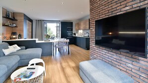 Una sala de estar moderna con un sofá gris, una mesa de centro con revistas y un mueble de pared para televisión.