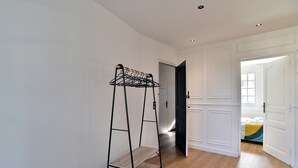 Un pasillo con un perchero de metal y una puerta que da a un dormitorio.