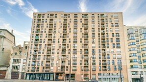 A multi-story residential building with balconies, a ground-level entrance, and a clear sky. - Blue Light - Appt pour 4p, Paris (Paris)