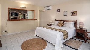 Een slaapkamer met een bed, nachtkastjes, een spiegel en een wandairconditioner.