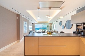 A modern kitchen with a central island, pendant lighting, and a view to a balcony.