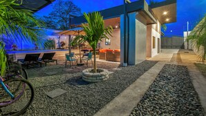 A modern outdoor patio area with seating, a small tree, and a bicycle. - La Casa de Papi (Parrita)