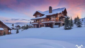 A large, multi-story wooden lodge with a snow-covered roof, surrounded by trees and snow, indicating a winter setting. - The BEST Ski In/Out! Immediately next to Montage! (Big Sky)