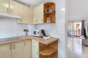 A modern kitchen with wooden cabinets, a microwave, and a coffee maker.