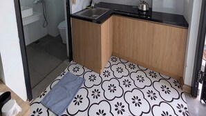 Uma cozinha compacta com bancada preta, armários de madeira e painel de azulejos.
