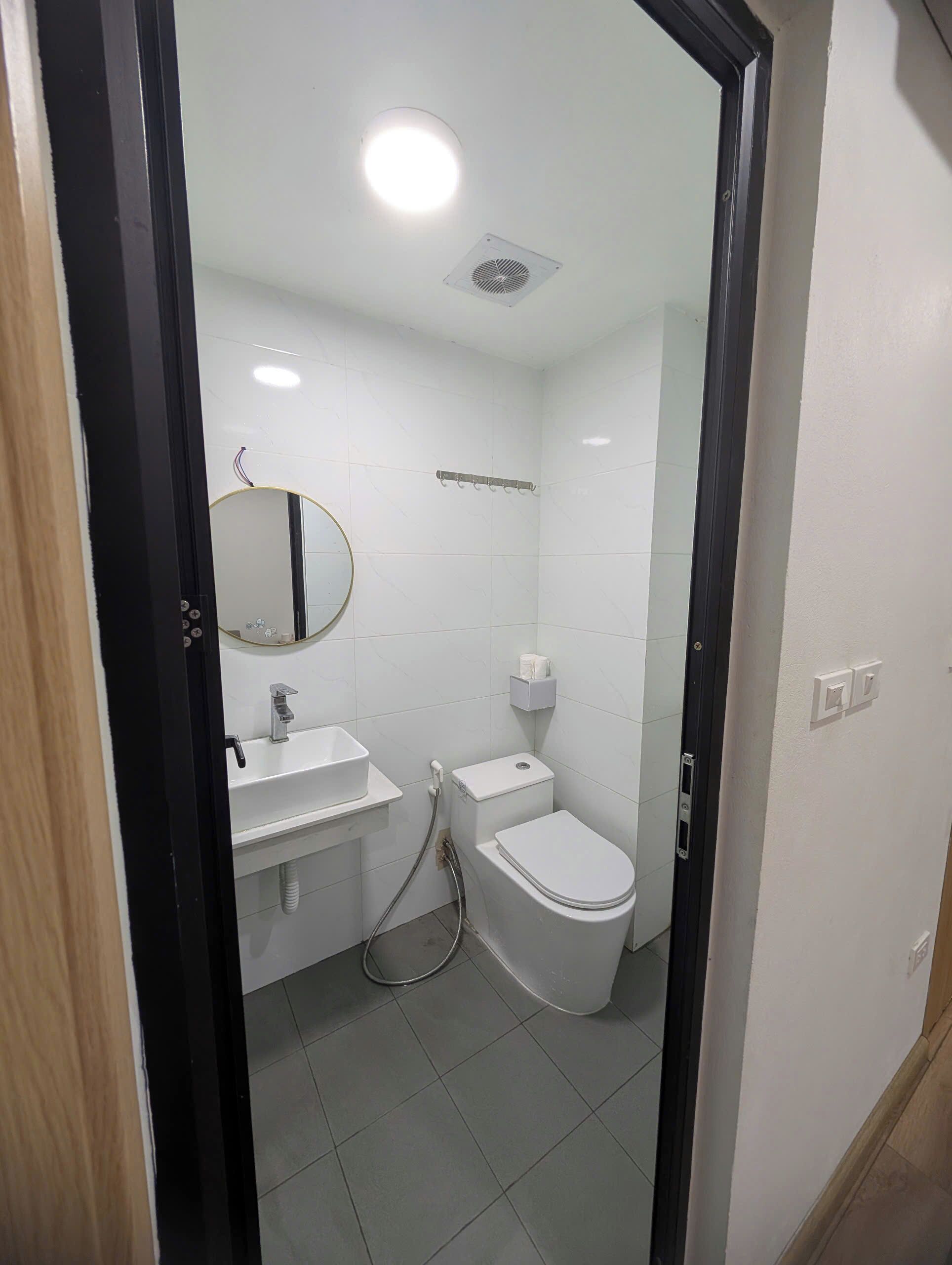 A small, clean bathroom with a toilet, sink, and mirror.