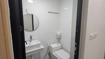 A small, clean bathroom with a toilet, sink, and mirror.