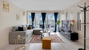 Una sala de estar moderna con un sofá gris, una mesa de centro y un televisor.