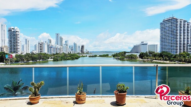 A waterfront view with high-rise buildings, a river, and potted plants on a balcony. - PARCEROS GROUP - 2 BEDROOM VACATION APARTMENT, 14TH FLOOR, CARTAGENA, SPAIN (Cartagena de Indias)