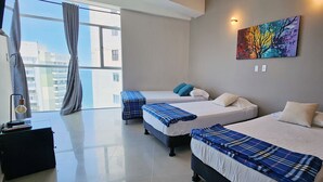 A modern hotel room with two beds, a large window with curtains, a painting on the wall, and a small table with a lamp. - PARCEROS GROUP - 2 BEDROOM VACATION APARTMENT, 14TH FLOOR, CARTAGENA, SPAIN (Cartagena de Indias)