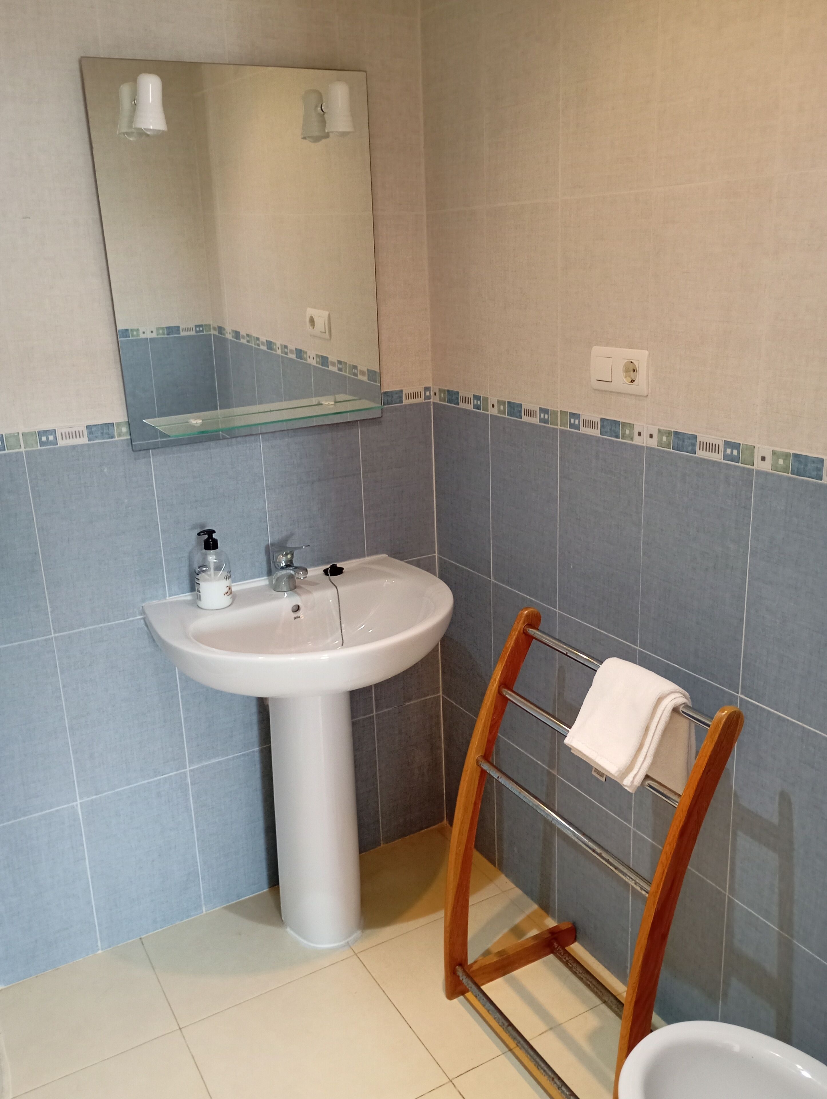 A bathroom with a white sink, a mirror above it, and a towel rack with a white towel.