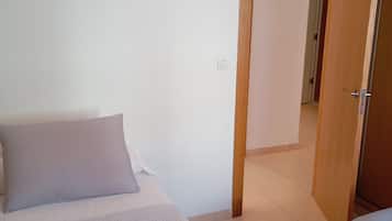 Une chambre à coucher avec un lit, une serviette rouge et une porte en bois donnant sur une autre pièce.