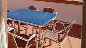 Une terrasse avec une table et des chaises donnant sur une plage.