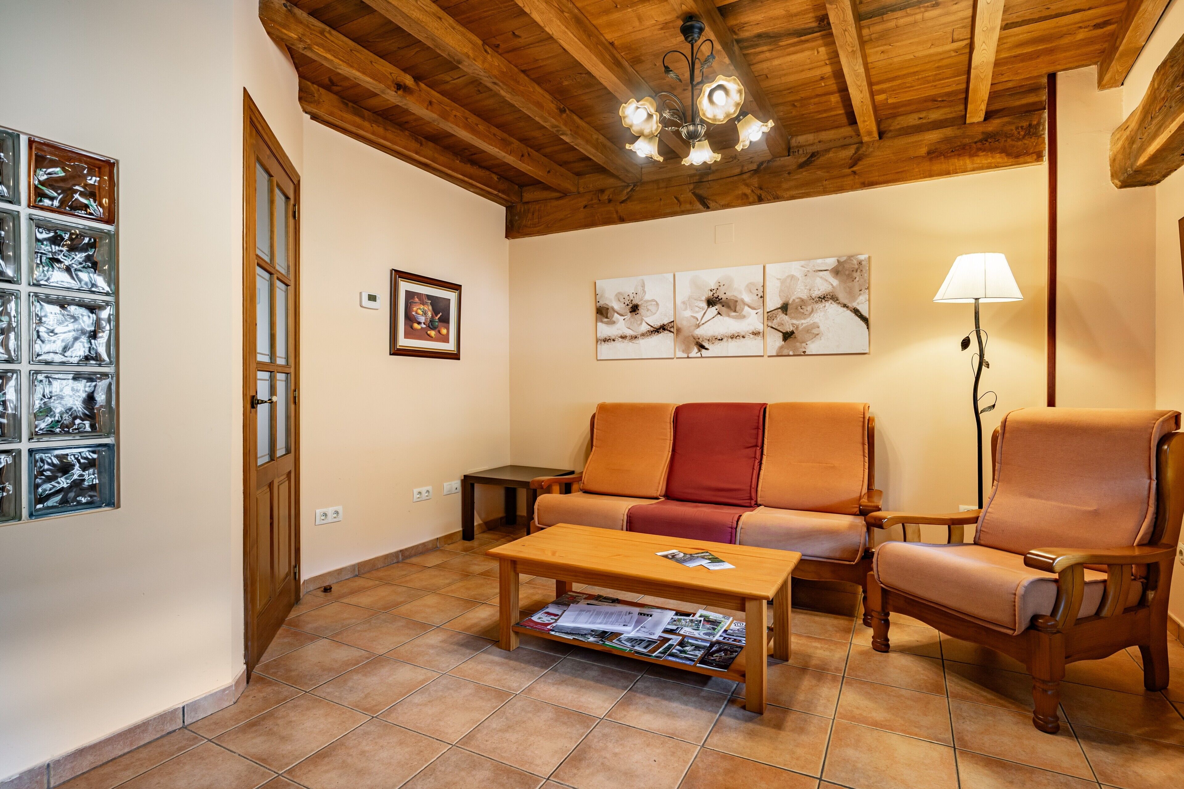 A living room with a wooden ceiling, a sofa, a chair, a coffee table, and a floor lamp.