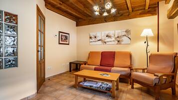 A living room with a wooden ceiling, a sofa, a chair, a coffee table, and a floor lamp.
