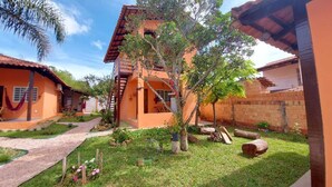 A courtyard with a central tree, a hammock, and a brick wall. - Chalés Flor de Manacá (Alto Paraíso de Goiás)