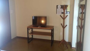 A room with a wooden TV stand, a mirror with a wooden frame, and a wall-mounted bulletin board. - Chalés Flor de Manacá (Alto Paraíso de Goiás)