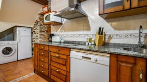 Cozinha com lava-louças, micro-ondas e parede de pedra.